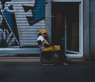 Donna preoccupata seduta davanti a una saracinesca