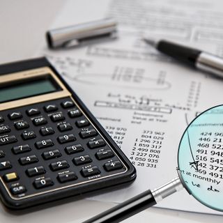 Conti, calcolatrice e una lente di ingrandimento su una scrivania