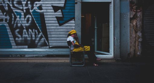 Donna preoccupata seduta davanti a una saracinesca Donna preoccupata seduta davanti a una saracinesca